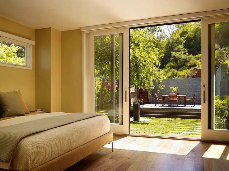 a bed sitting in a bedroom next to a sliding glass door that leads to a patio