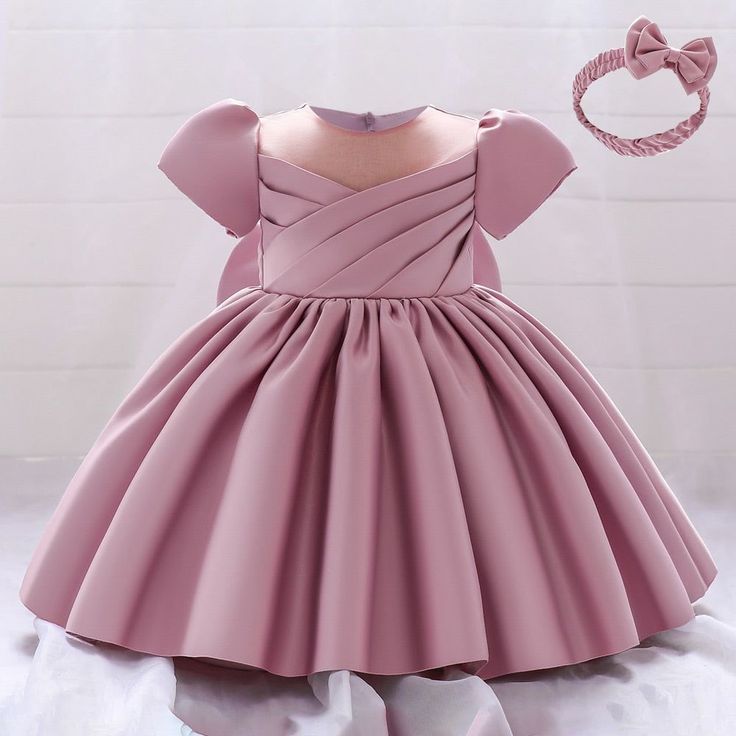 a pink dress is shown with a bow on the headband and it's made out of fabric