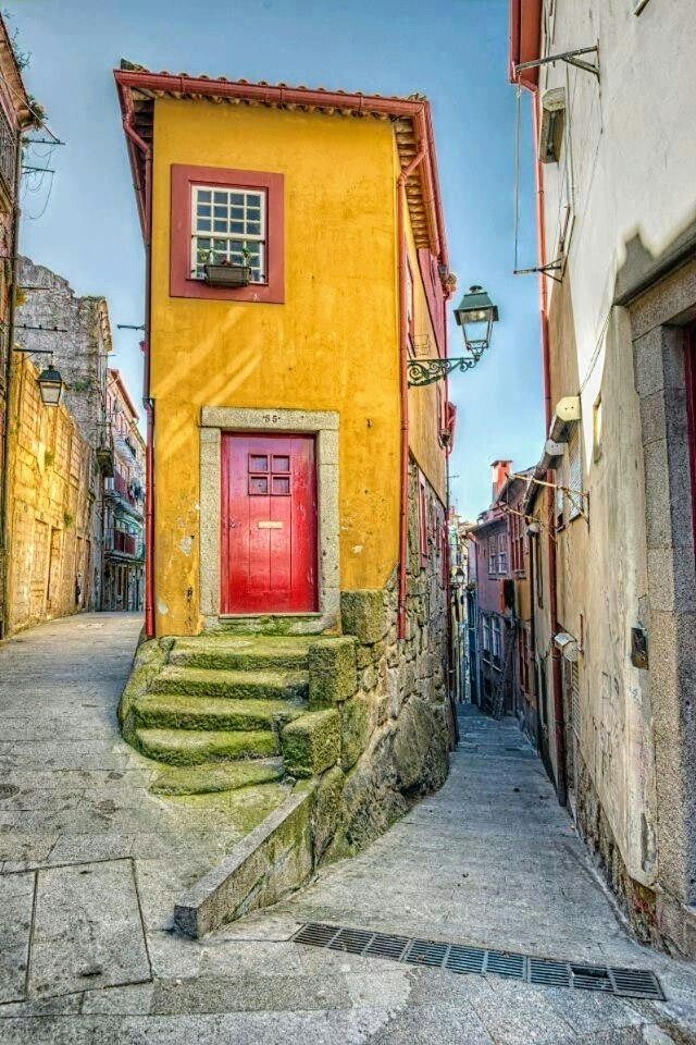 an alleyway with steps leading up to a red door and yellow building in the background