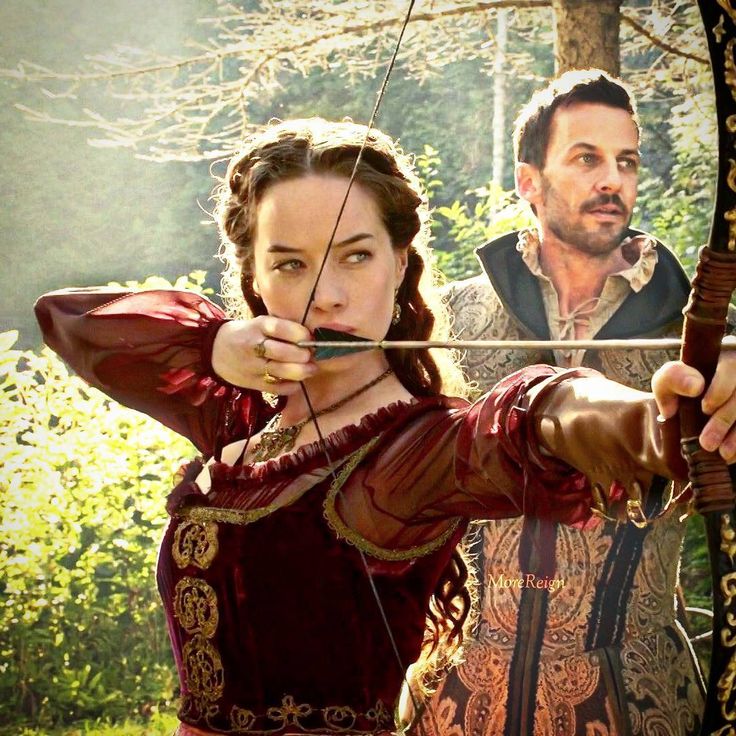 a man and woman dressed in medieval clothing aiming at an arrow