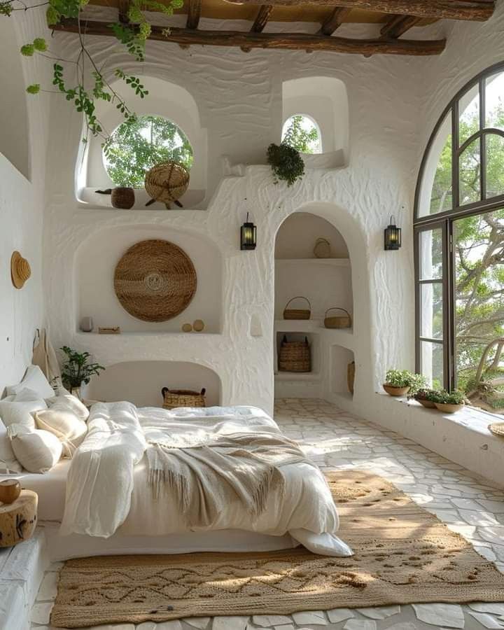 a bedroom with an arched window and white walls is pictured in this image, there are plants growing on the windows sill