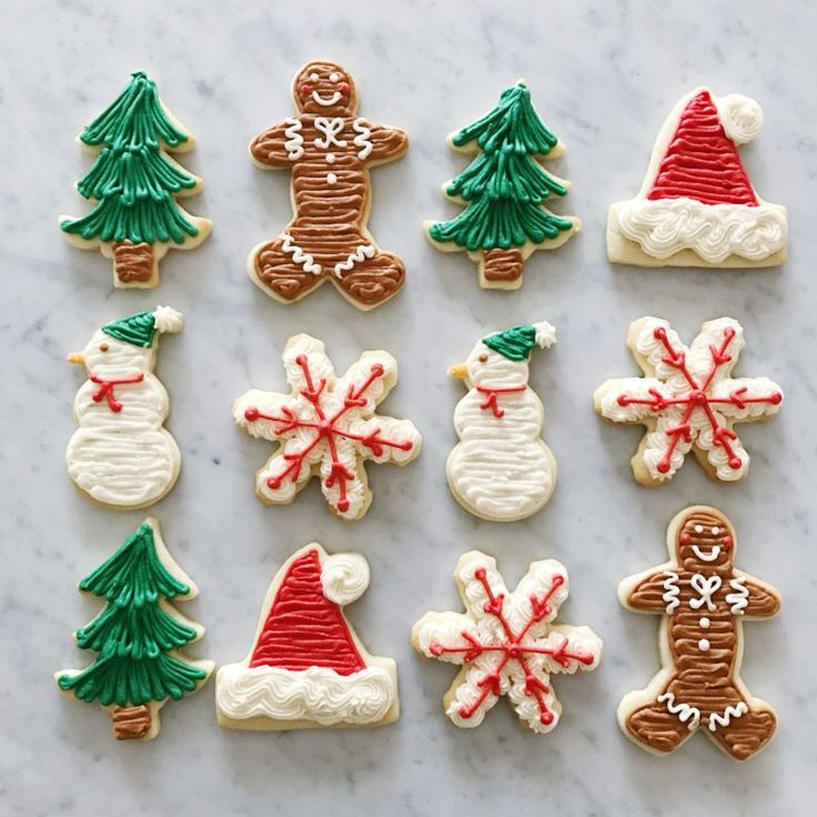 cookies decorated like christmas trees, snowmen and santa hats are displayed on a table