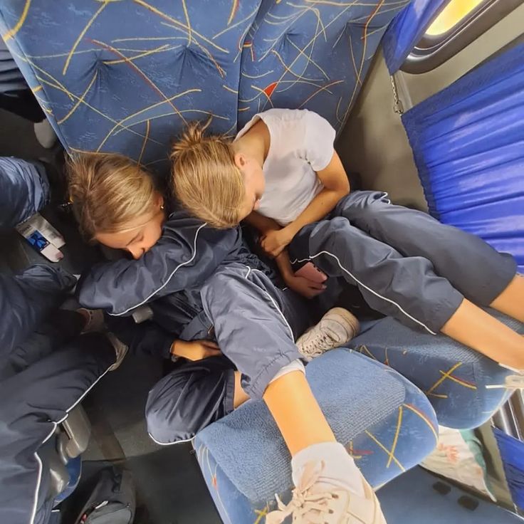 two young boys are sitting on a bus and one boy is holding his arm around the other