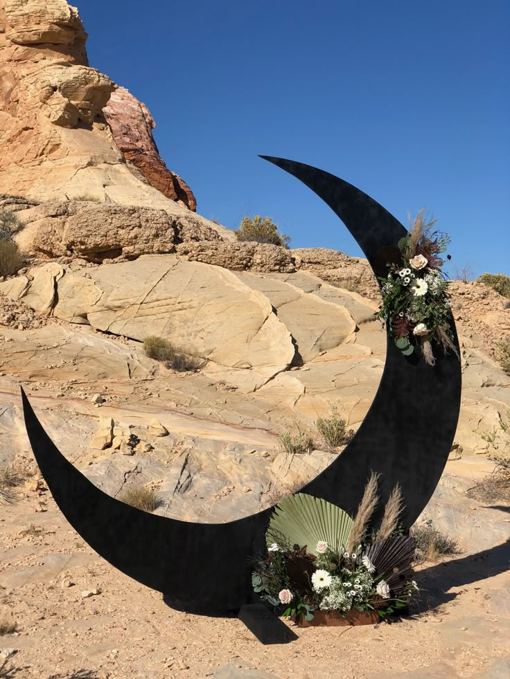 a crescent shaped sculpture with flowers on it in the desert