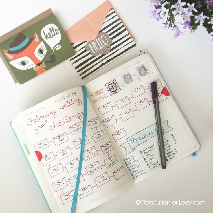 an open notebook sitting on top of a table next to a pen and flower pot