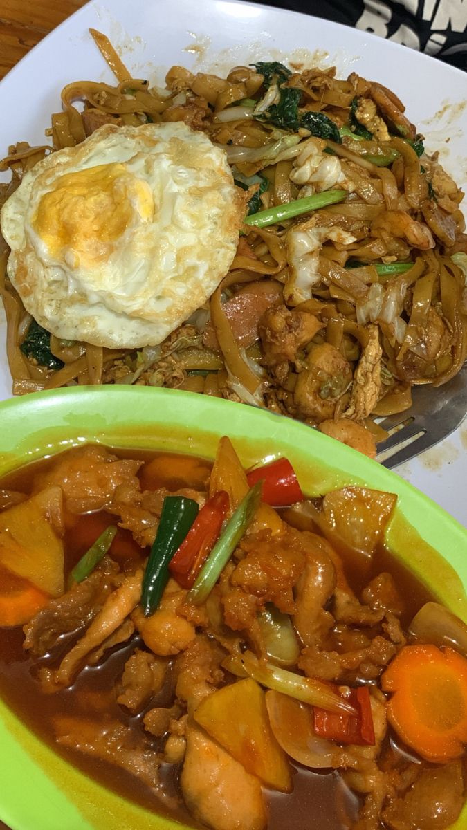 a plate with meat and vegetables on it next to a bowl of fried egg in sauce