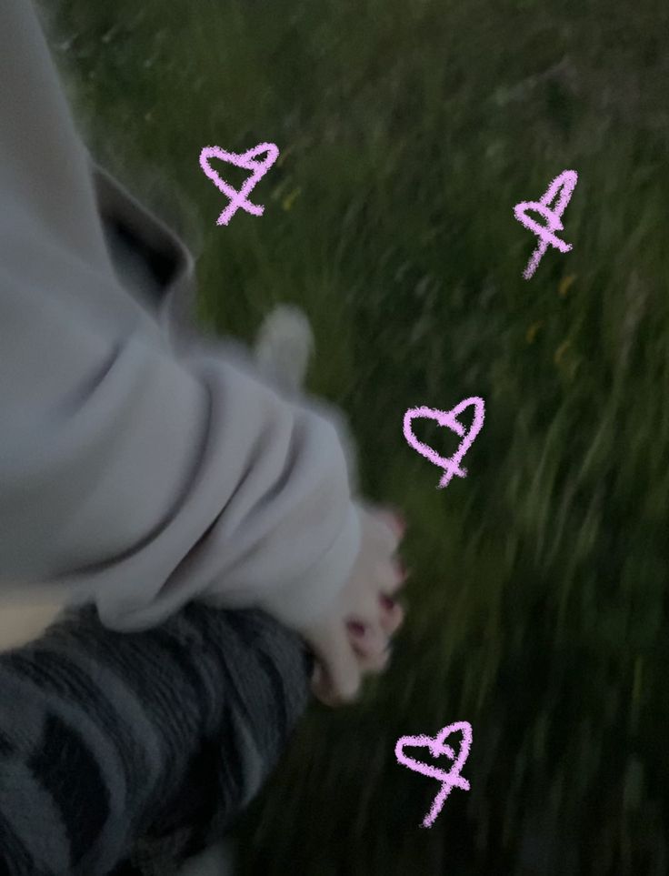 someone is holding their hand out in front of the camera with hearts drawn on it