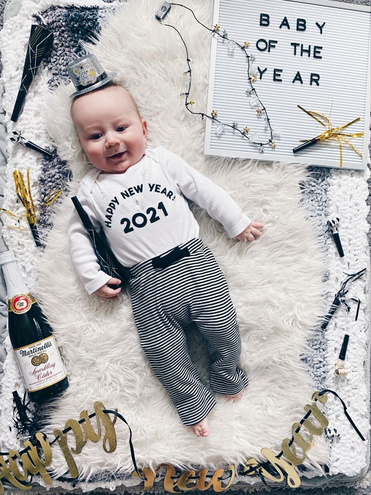 a baby laying on top of a white fluffy blanket next to a bottle of wine