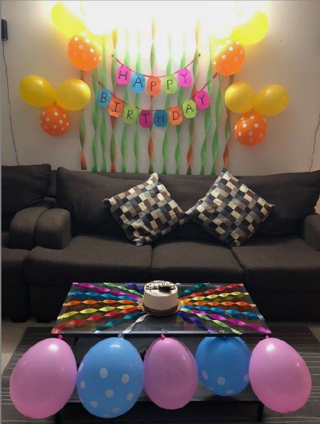 a living room decorated with balloons, streamers and a birthday cake on the coffee table