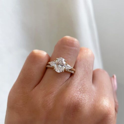 a woman's hand holding an engagement ring with two pear shaped diamonds on it