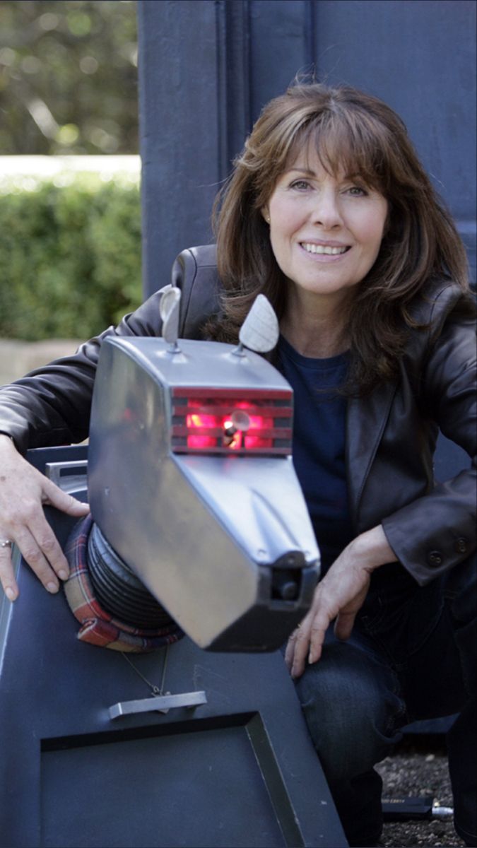 a woman sitting on the back of a truck holding an object in her hand and smiling at the camera