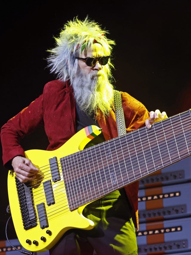 a man with long white hair holding a yellow guitar