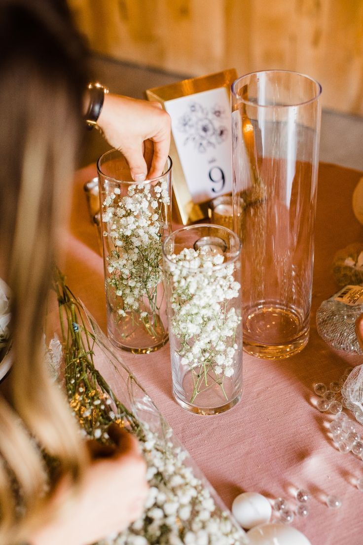 a table topped with vases filled with baby's breath next to candles and flowers