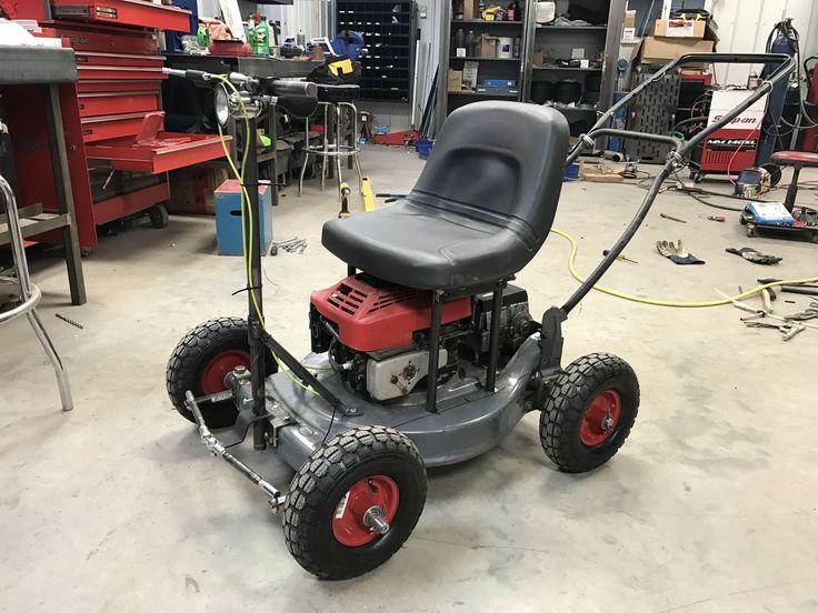 a lawn mower sitting in a garage with red wheels on the front and black seat