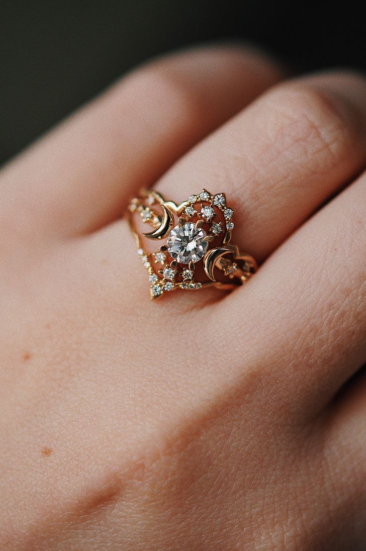 a woman's hand with a gold ring on top of it and a diamond in the middle