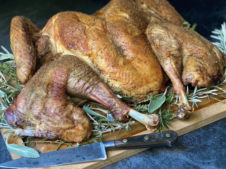 a roasted turkey on a cutting board with herbs