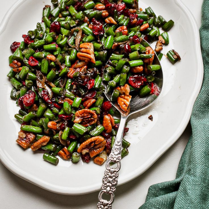 a white plate topped with green beans and cranberry sauce next to a spoon