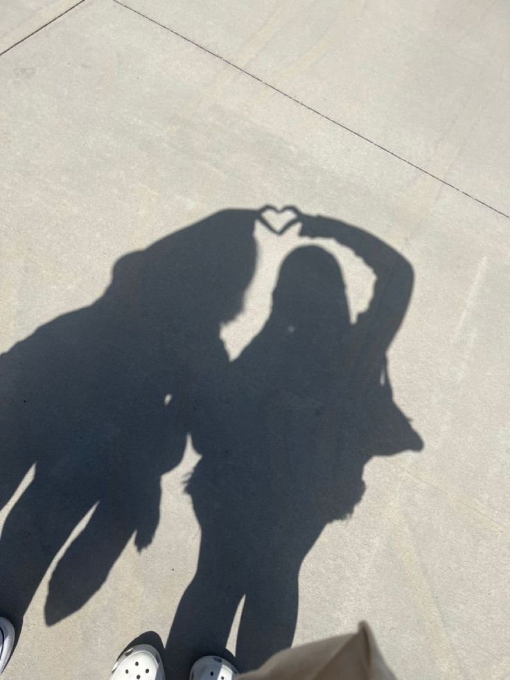 the shadow of two people standing next to each other in front of a skateboard