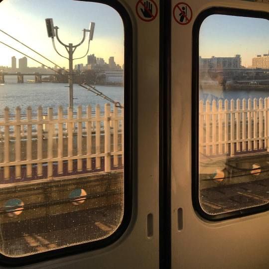 the view from inside a train looking out at water and cityscape in the distance