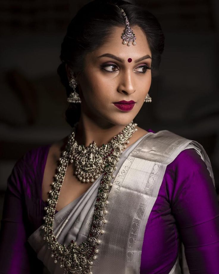 a woman in a purple and white sari with jewels on her neck, wearing a necklace