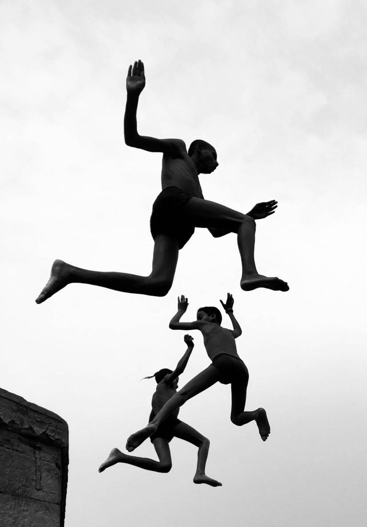 three people are jumping in the air with their hands up