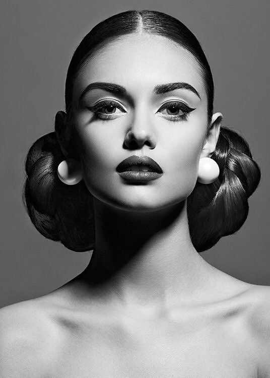 a black and white photo of a woman's face with her hair in a bun