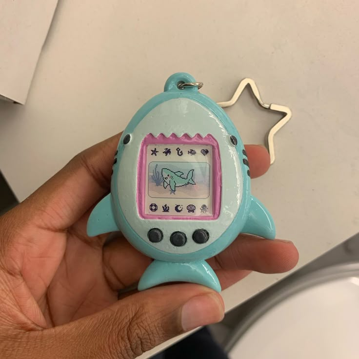 a hand holding a small toy with a screen on it