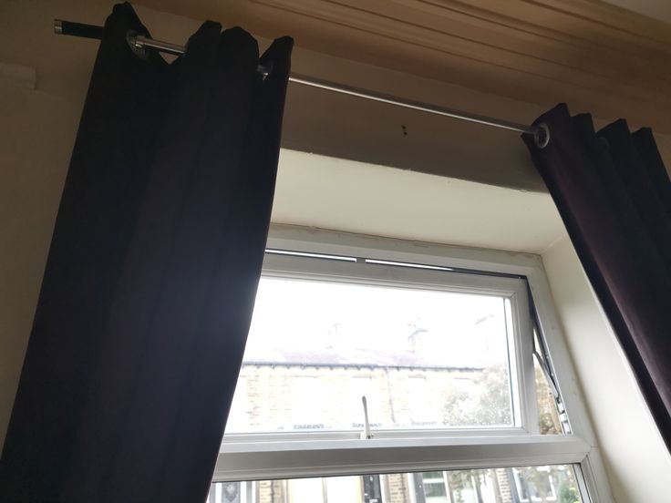 an open window with black curtains in front of it