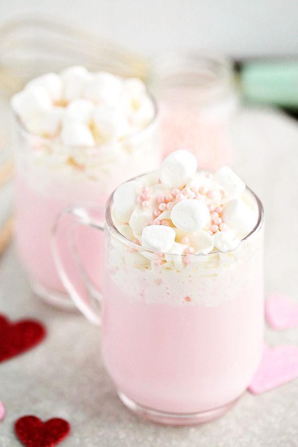 two cups filled with marshmallows on top of a table