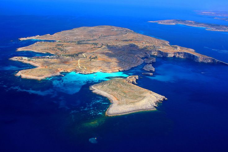 an island in the middle of the ocean with blue water and landforms around it