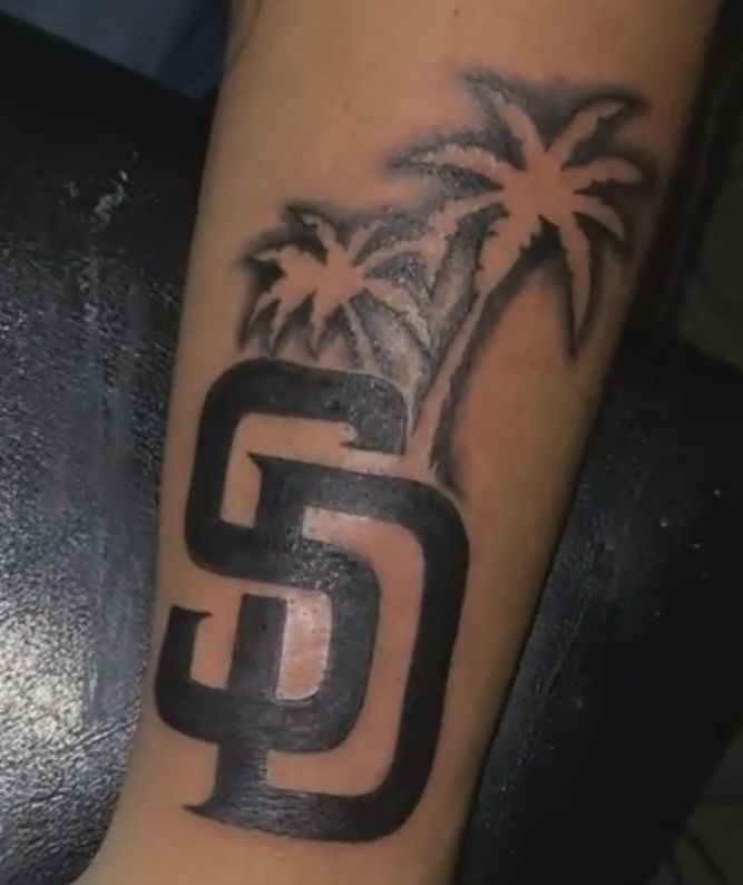 a man's arm with a palm tree and the letter g on it, in black ink