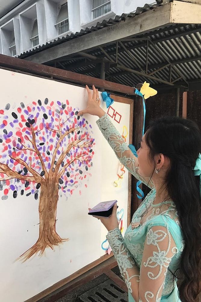 a woman is painting a tree on a white board