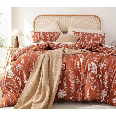 a bed with an orange comforter and pillows