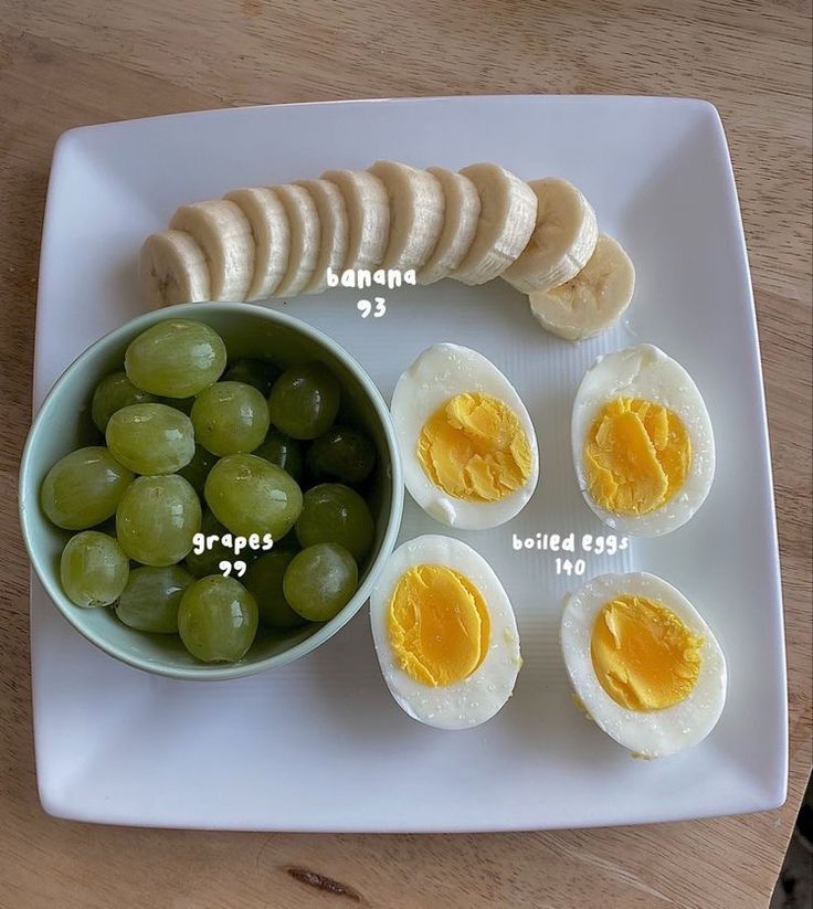 a plate with grapes, hard boiled eggs and sliced bananas