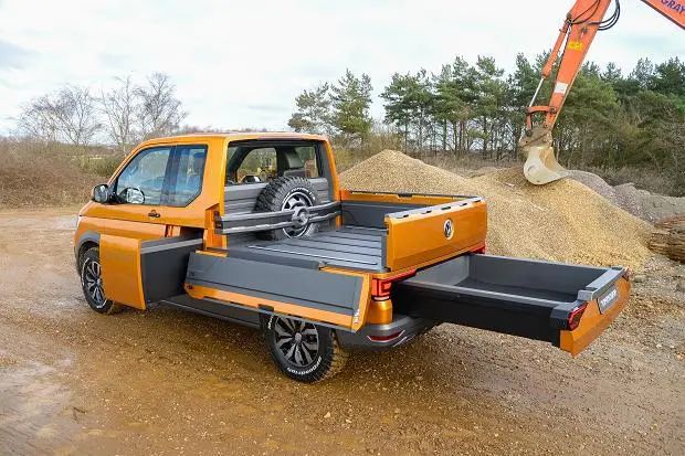 an orange truck parked on top of a dirt road next to a pile of dirt