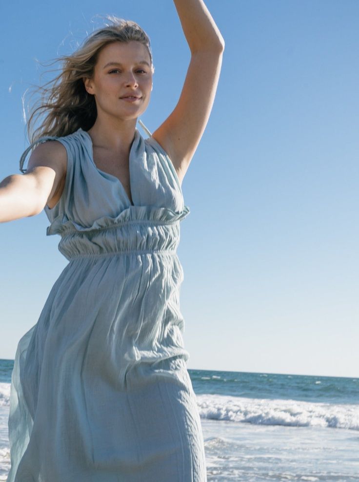 Ethereal and the color of blue skies and lapping waves. Our Goddess dress is light and airy with drawstring shoulder and ruched elastic empire waist detailing. 100% cotton deadstock cotton voile One Size S/M Chest width flat 18" Empire elastic waist flat 13", stretches to 19" Hip width flat 24" Body length from shoulder 42" Fully lined Hand wash cold, line dry, or dry clean Consciously made in small batches in sunny California using deadstock fabrics and recycled materials. Seasonless essentials Breezy Ruched Maxi Dress For Summer, Breezy Summer Maxi Dress With Ruched Detail, Summer Breezy Ruched Maxi Dress, Blue Smocked Dress With Gathered Neckline For Summer, Summer Maxi Length Dress With Drawstring, Flowy Ruched Dress For Beach Season, Breezy Ruched Dresses For Spring, Flowy Dress With Smocked Bodice For Beach Season, Flowy Smocked Bodice Dress For Beach Season