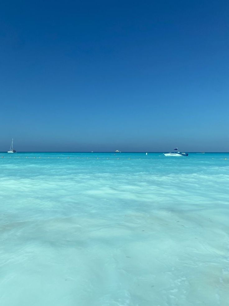 the water is very clear and blue with boats in the distance