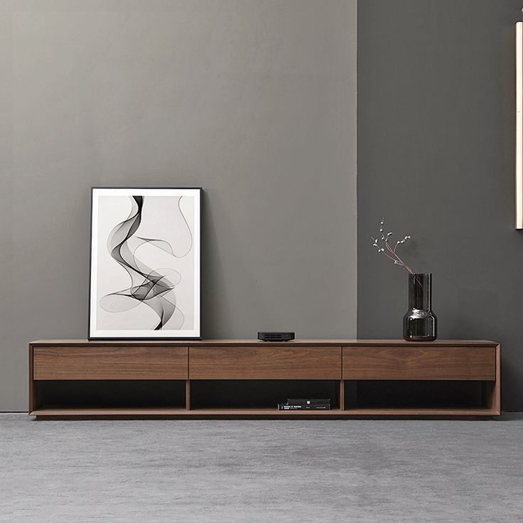 a modern entertainment center with an abstract painting on the wall and vase in front of it