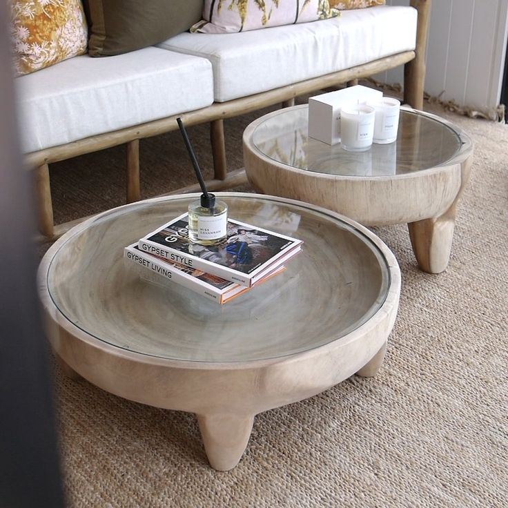 two coffee tables sitting on top of a carpeted floor next to a white couch