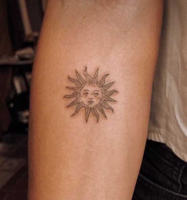 a woman's arm with a small sun tattoo on it