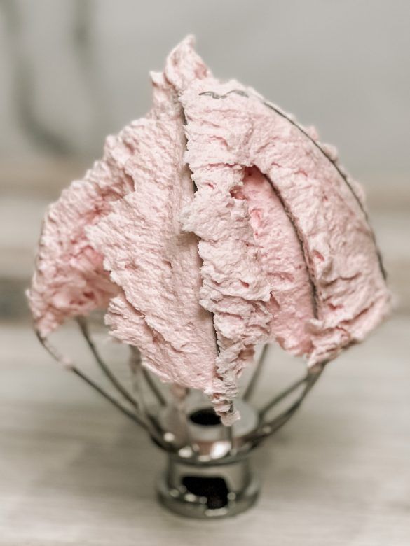 a close up of a pink frosted pastry in a metal stand on a table