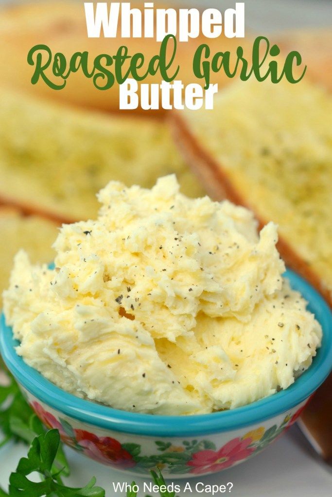 whipped roasted garlic butter in a blue bowl with parsley on the side and toasted bread behind it