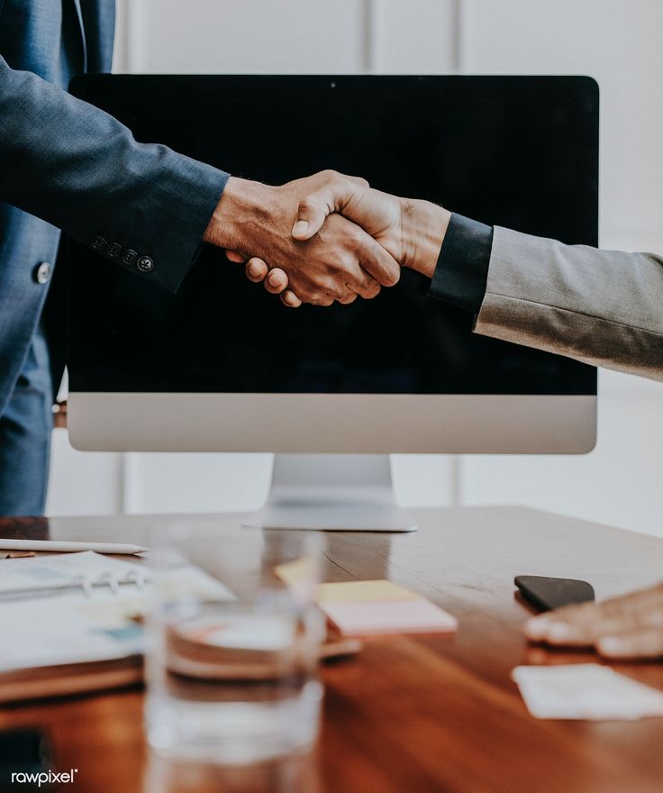 two people shaking hands over a computer screen