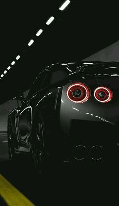 the rear end of a black sports car in a dark tunnel