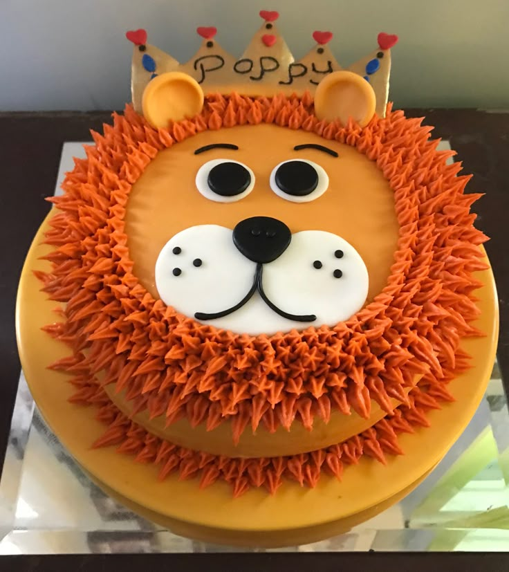 a lion cake with orange icing and decorations on it's face is sitting on a table