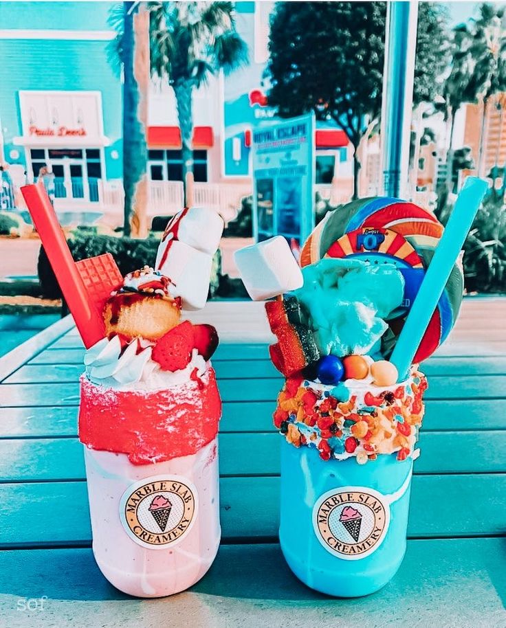 two ice cream sundaes sitting on top of a wooden table next to each other