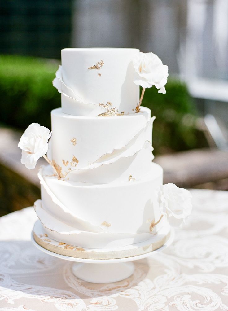 a three tiered white cake with flowers on the top is sitting on a table