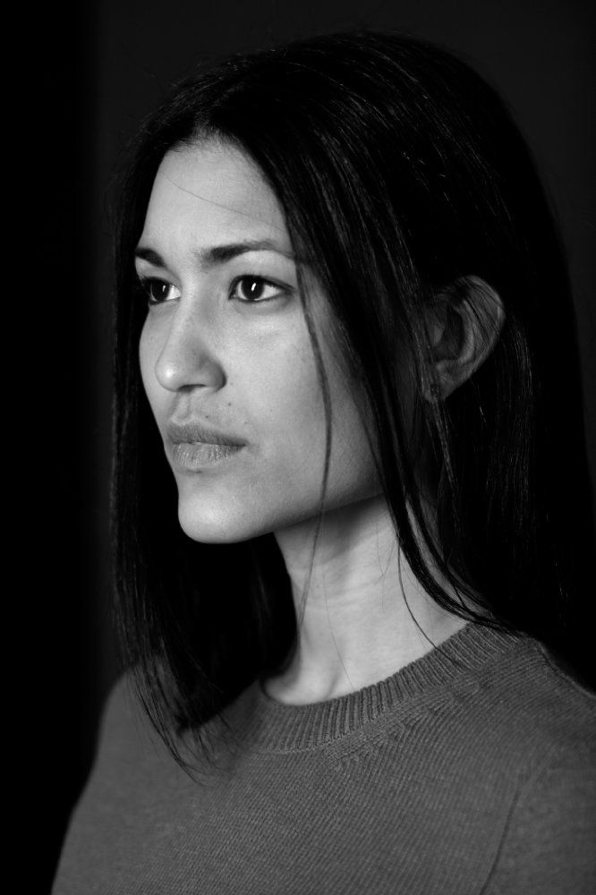 a black and white photo of a woman in a sweater looking at the camera with an intense look on her face