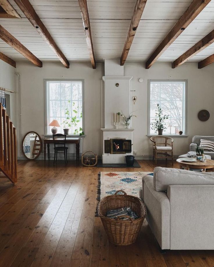 a living room filled with furniture and a fire place next to a wooden floored wall