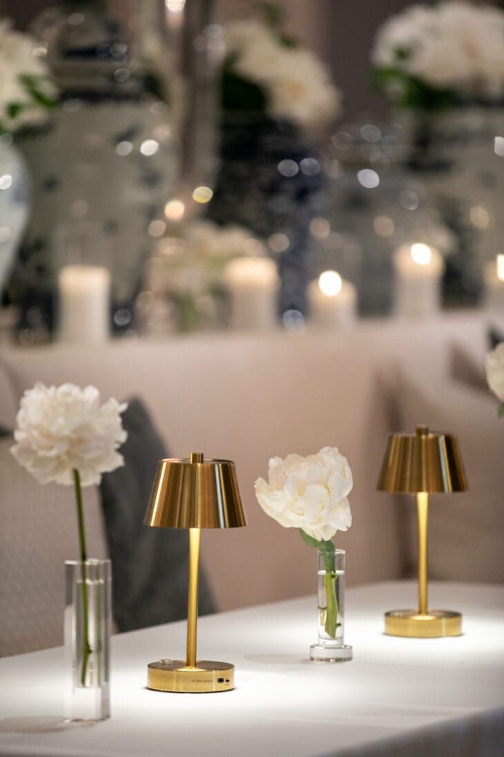 three vases with flowers and candles on a table